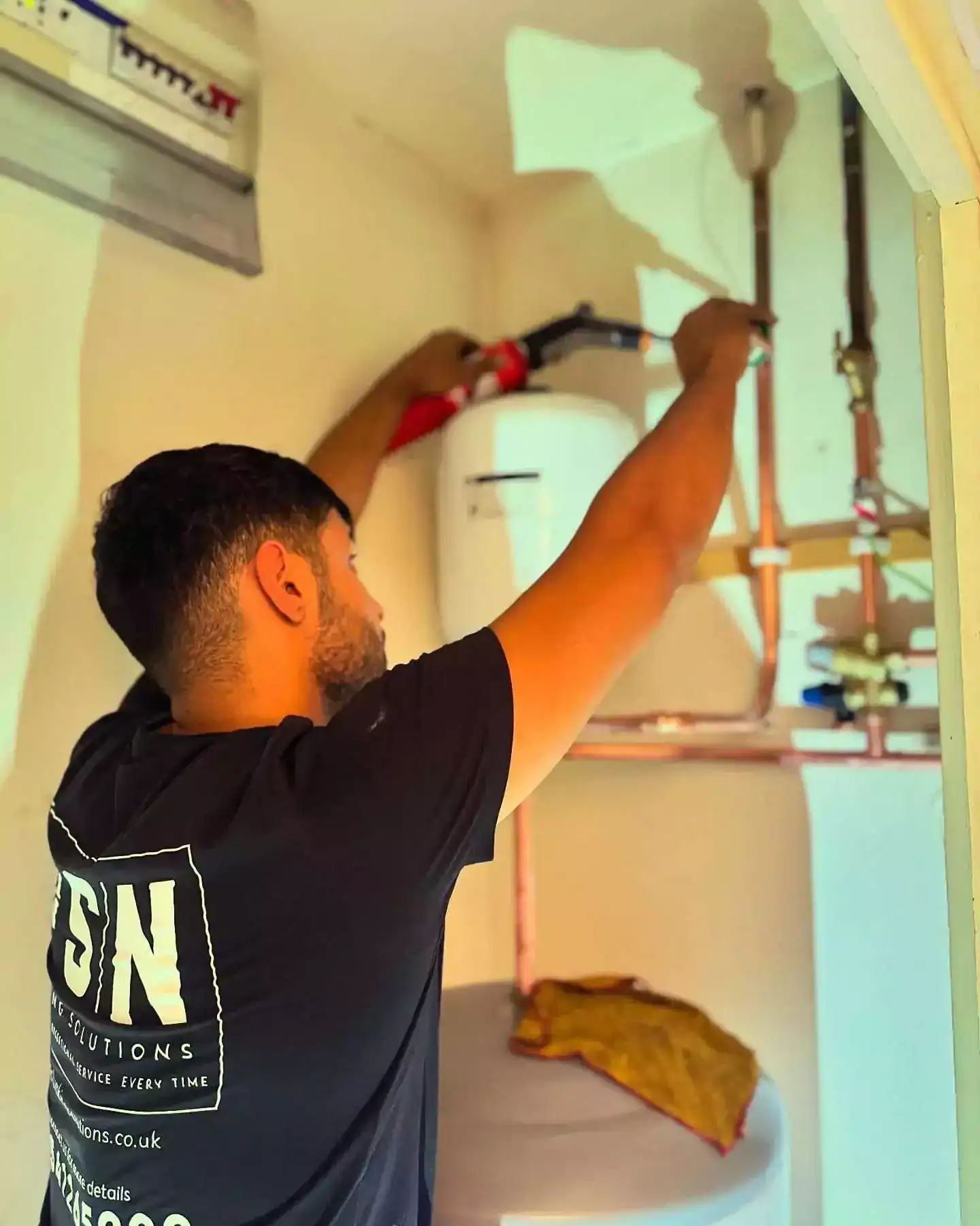 Plumbing technician installing pipes and fittings in a home.