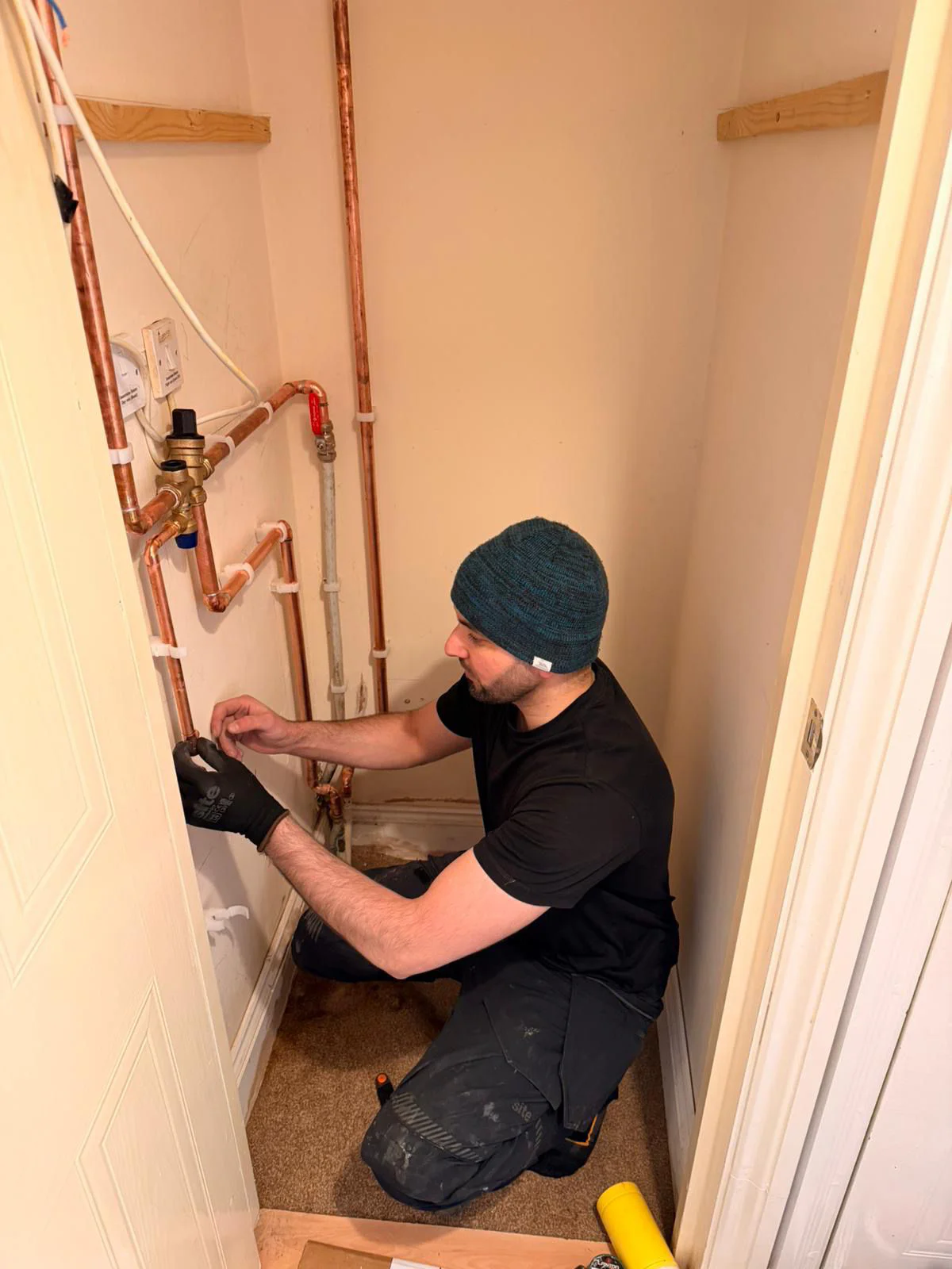 Pipework installation in a small utility closet for plumbing system setup.